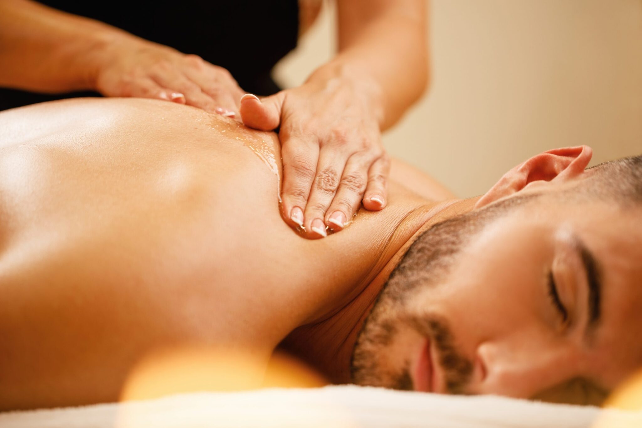 Close-up of man having back massage with honey at health spa.